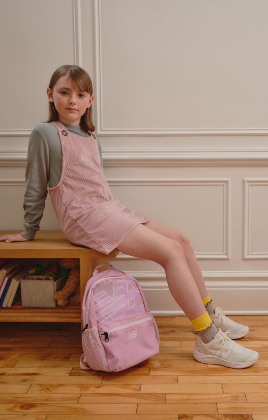 A child sitting on a chair and wearing new balance fresh foam x  Arishi v4 running shoes
